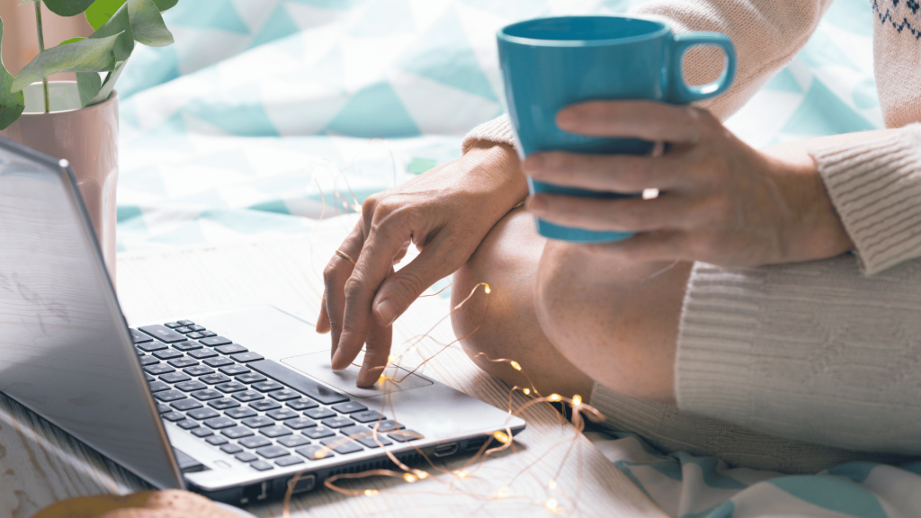 A woman holding a cup on her hand while using her laptop
