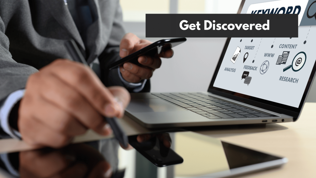 A man holding holding his phone while working on his tablet and laptop