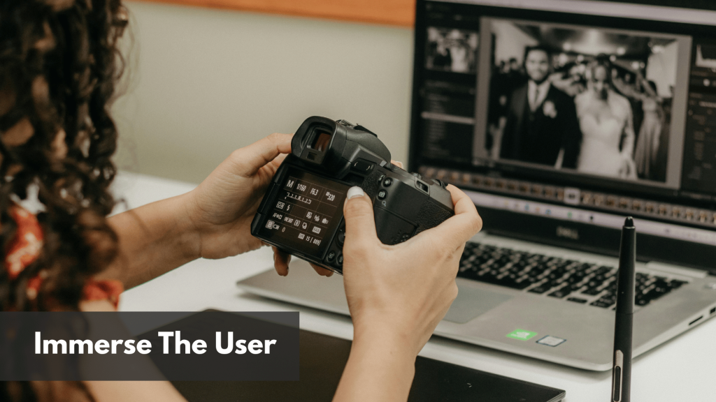 A lady holding her camera while editing an image in her laptop