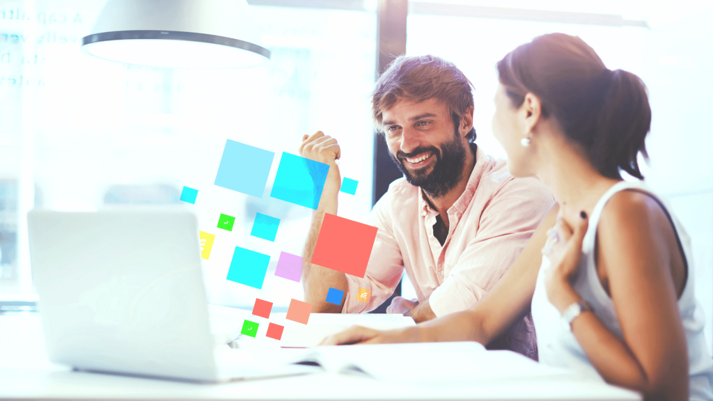 Two colleagues smiling at laptop with colorful digital icons overlayed, representing creative collaboration.